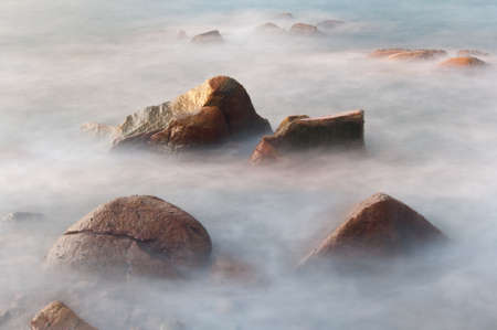dramatic rock in sea under long exposureの写真素材
