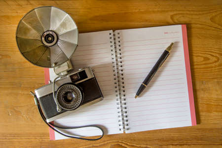 Blank notebook with fountain pen and retro camera on wooden tableの写真素材