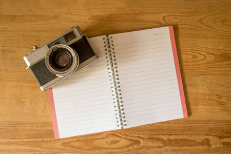 Blank notebook with fountain pen and retro camera on wooden tableの写真素材