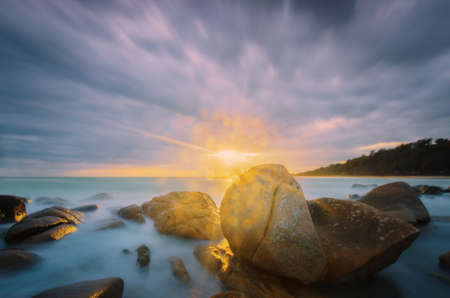 Light ray and rock bokeh beautiful in sunset seascape.の写真素材