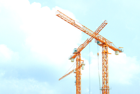 Two orange crane in cross on blue skyの写真素材