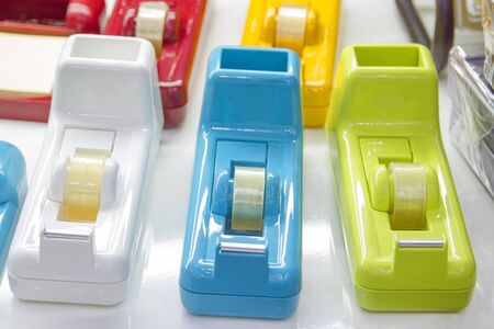 3 multi-colored tape dispensers placed on a white deskの写真素材