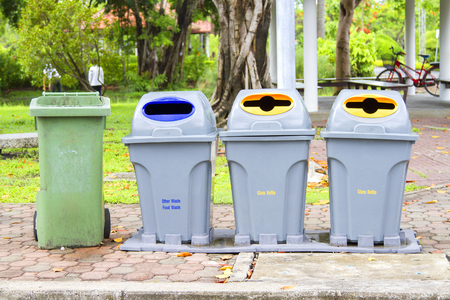 Four bins are on the sidewalk in the park.の写真素材