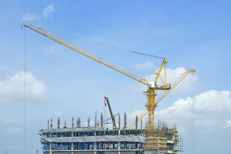 Crane lifts building with construction workers.の写真素材