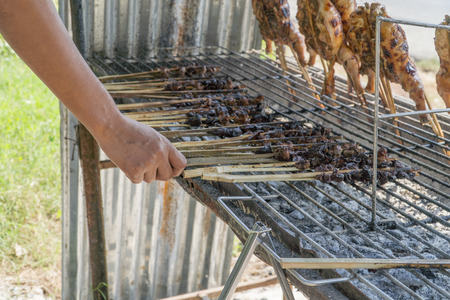 hand keep grilled chicken and grilled liver on the grill.の写真素材