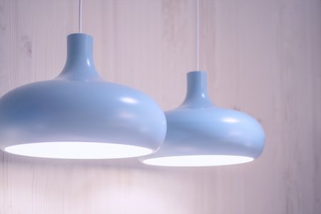 blue lamp hanging on the white cable on wall backgroundの写真素材