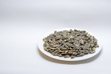 Dried sunflower seeds in the white plate on white background.の写真素材