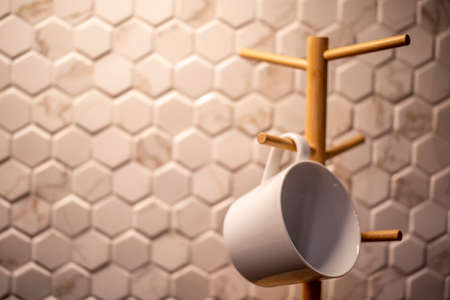 Coffee mugs hanging on a wooden cup holder.