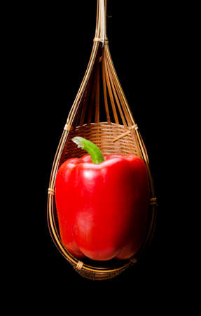 Still life with Red capsicum are placed in a wooden basket, isolated on blackの写真素材