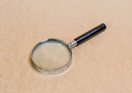 Old magnifying glass on vintage paper backgroundの写真素材