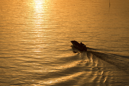 Golden sunset effect on water with passing boat in silhouette.