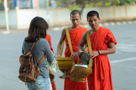 Luang Prabang, Laos - circa December 2015: Traditional Alms giving ceremony of distributing food to...
