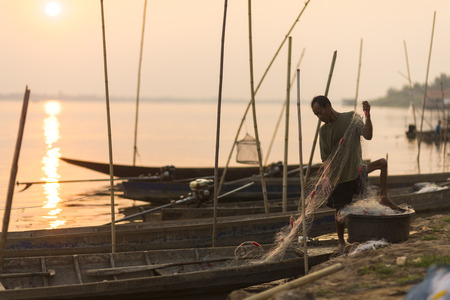 MAY, 2015 - Mae Sai, Thailand: Man fishing into the Mekong river on his long tail boat.のeditorial素材