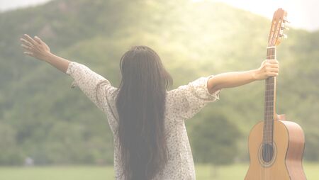 Artist girl with a guitar in the gardenの写真素材