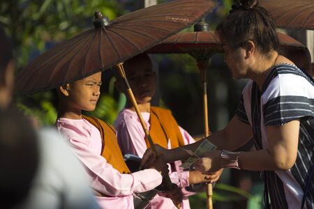 KANCHANABURI, THAILAND - APRIL 24: Buddhist monk walks on Auttamanusorn Wooden Bridge (Mon Bridge) with group of Mon students at Sangklaburi, Kanchanaburi, Thailand on November 24, 2016のeditorial素材