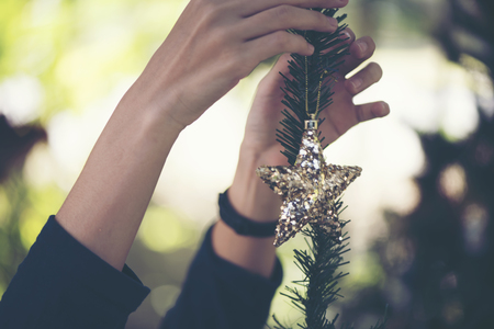 women hand setting decorations and gift boxes on Christmas treeの写真素材