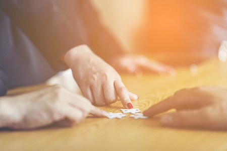 Businesspeople Hand Solving Jigsaw Puzzle On Wooden Desk, business conceptの写真素材