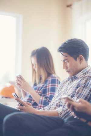Closeup Group Adult Hipsters Friends Sitting Sofa Using Hands Modern Smartphone Tablet.Business Startup Friendship Teamwork Concept.People Working Together Project.Coworking Process Studio.Blurredの写真素材