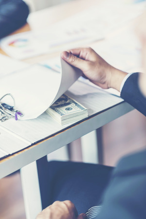 Bribery and corruption concept, bribe in the form of dollar bills, Businessman giving money while making deal to agreement a real estate contract and financial corporate.の写真素材