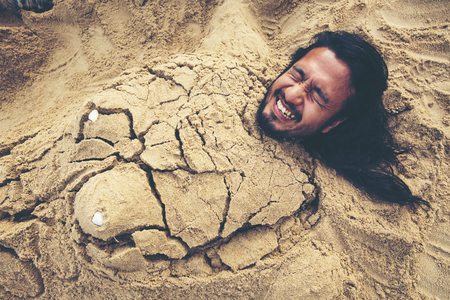 Man buried in the sand at the beach. concept happiness, vacation, no problem, everything is fine.の写真素材
