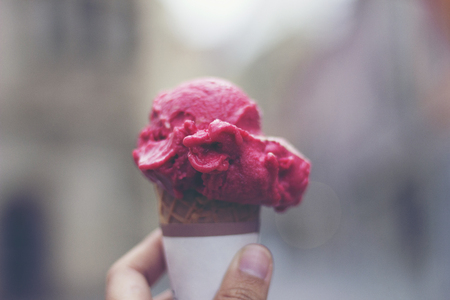 Woman's hands holding melting ice cream waffle cone in hands on summer light