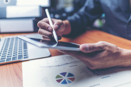Attractive Young Office businessman Working on the Business Papers While Leaning on him Desk.の写真素材