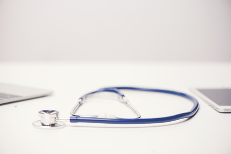 Workplace of doctor with laptop and stethoscope and notebook on white table top view shot.の写真素材