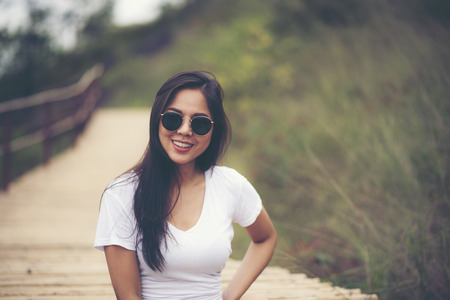 Summer girl portrait. Asian woman smiling happy on sunny summer or spring day outside in parkの写真素材