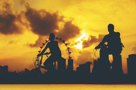 The silhouette of a businessman is cycling with sunset, Singaporeの写真素材