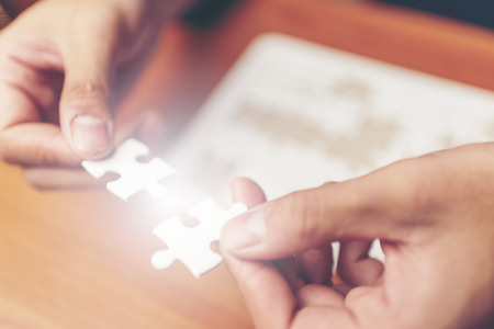 Man hands connecting couple puzzle piece in office. Business solutions, target, successful, goals and strategy conceptsの写真素材