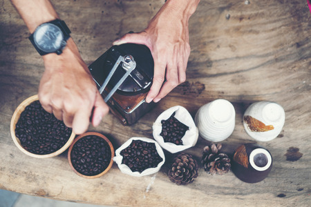 Barista is grinding coffee with a hand coffee grinder.の写真素材
