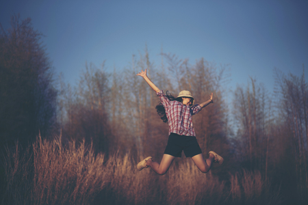 Happy woman jumps to the sky in the yellow meadow at the sunsetの写真素材