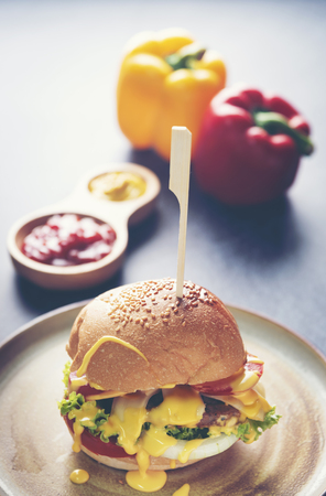 A delicious grilled Angus burger with cheese, lettuce, and tomato on a sesame seed bunの写真素材