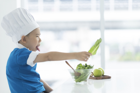 Child chef are happy with fresh vegetablesの写真素材