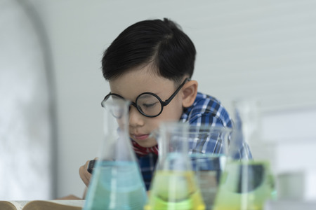 children boy studying the chemical solution in the laboratory using a glassware.