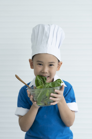 Child chef are happy with fresh vegetablesの写真素材