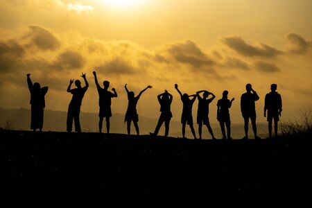 The silhouette of a group of people is celebrating success on the hilltop.の写真素材