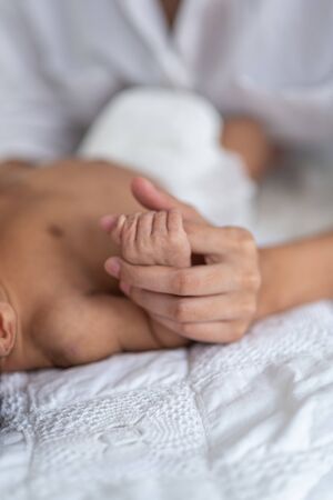 Portrait of beautiful mother playing with her 1 months old baby in the bedの写真素材