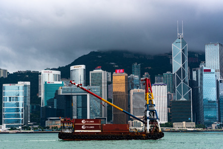 Hong Kong, China - August, 2019: A cargo ship in the bay of hong kong, modern building skyscraper in...