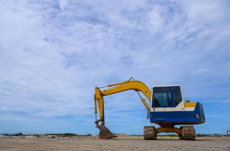 Yellow loader backhoe on pile dry wood chips with blue sky. Industrial in factory.