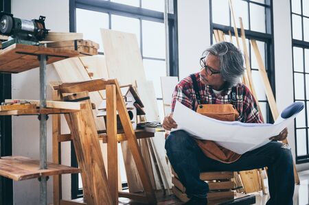 Background image of woodworking workshop: carpenters work table with different tools and wood cutting stand, vintage filter imageの写真素材