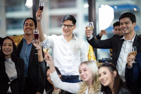 Toast to success. Group of business people toasting with champagne and smiling while standing close to eachの写真素材