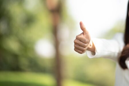 successful girl pointing thumb up; portrait of cheerful smiling woman pointing up approving, yes, ok, goodの写真素材