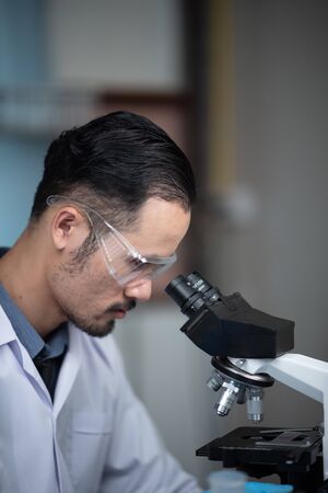 Young scientist looking through a microscope in a laboratory. Young scientist doing some research.の写真素材