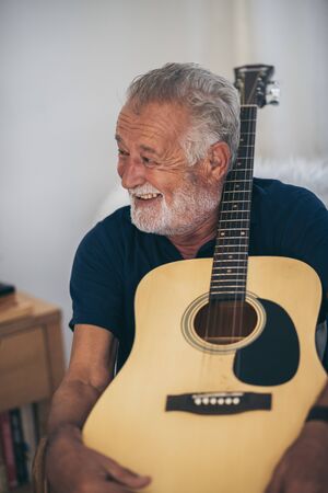 The old man and his guitar in the houseの写真素材