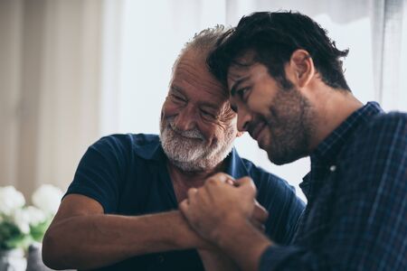 An adult hipster son and senior father at home, talking.の写真素材