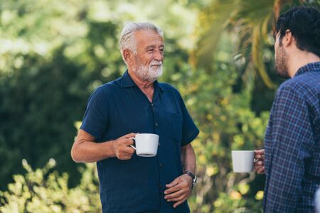 Old father and son, Morning coffee in a gardenの写真素材