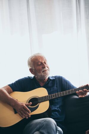 The old man and his guitar in the houseの写真素材