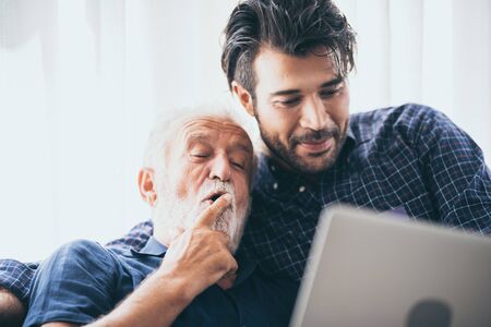 An adult hipster son and senior father at home, talking.の写真素材