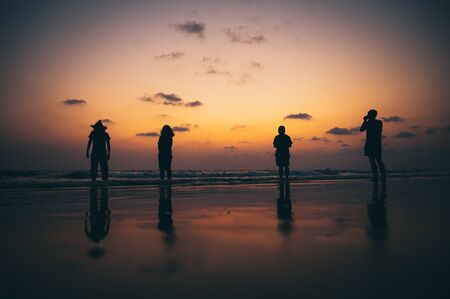 Silhouette of a group of friends Seaside during sunsetの写真素材